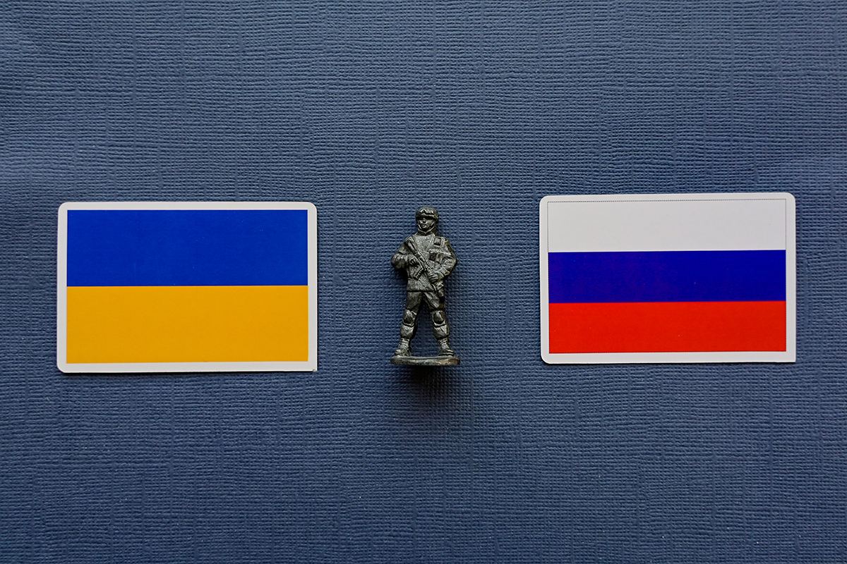 Знамена на Украйна и Русия с военна фигура между тях – илюстрация към новината за ударите